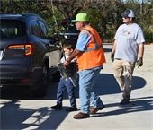Boy and man carrying a sapling to a car together