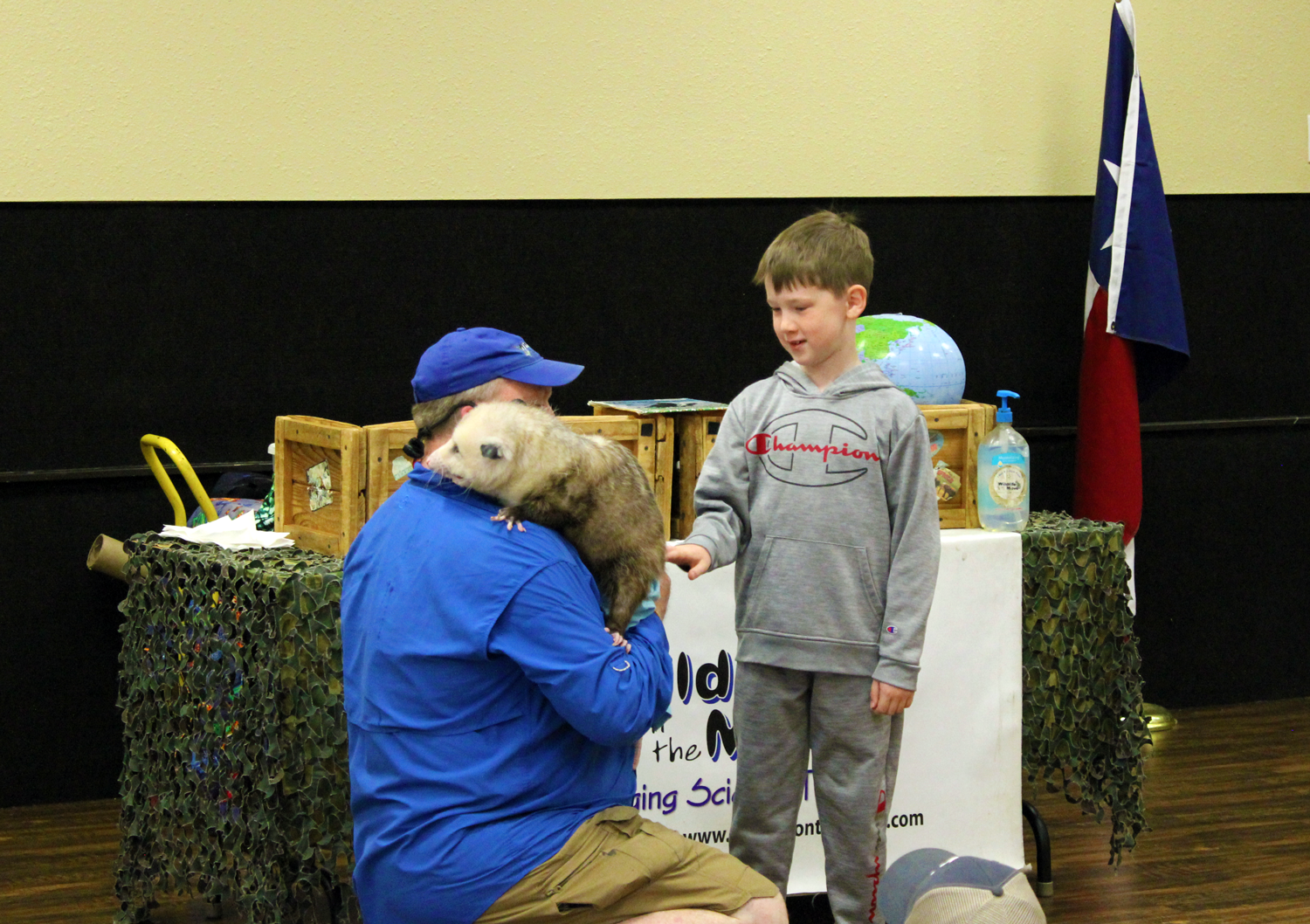 Presenter with opossum on his shoulder and a young boy petting it